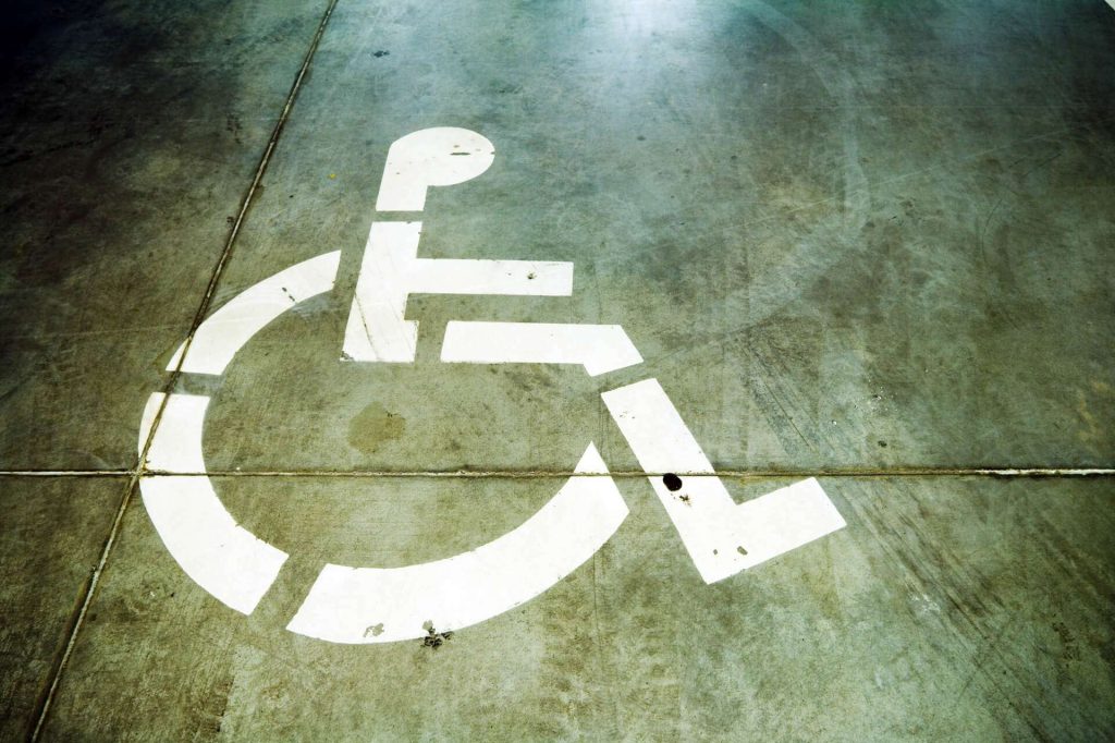 White wheelchair accessibility symbol painted on a concrete surface.