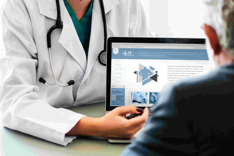 A healthcare professional discusses information on a laptop with a patient.